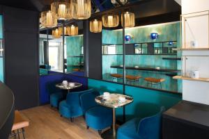 a restaurant with blue chairs and tables and chandeliers at Hotel Pilime in Paris