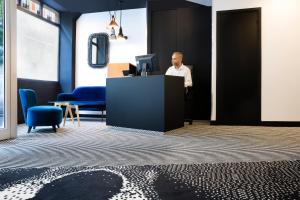 a man standing at a desk in front of a computer at Hotel Pilime in Paris