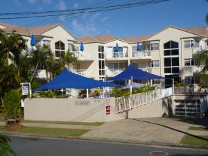 um edifício com guarda-chuvas azuis em frente em Le Lavandou Holiday Apartments em Gold Coast