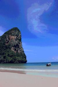 a boat on the beach with a rock in the water at Railay Village Resort in Railay Beach