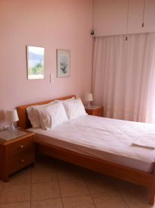 a bedroom with a bed with white sheets and a window at Posidonia Pension in Amarynthos