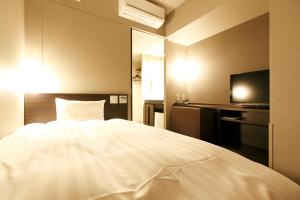 a bedroom with a white bed and a television at Dormy Inn Kagoshima in Kagoshima +60 photos