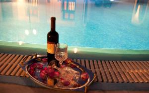 una botella de vino y una copa junto a la piscina en Villa Pelekanos, en Karterados