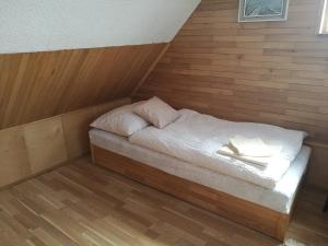 Ce petit lit se trouve dans un dortoir doté de murs en bois. dans l'établissement Apartman v zahrade, à Nová Včelnice
