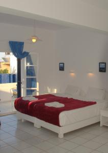 a bedroom with a large bed with a red blanket at Porto Bello Hotel Apartments in Milatos