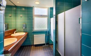 a green bathroom with two sinks and a window at Eurohostel in Helsinki