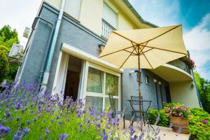 un parasol devant une maison avec des fleurs violettes dans l'établissement Csenge Villa, à Siófok