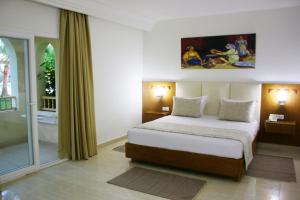 The Ksar Djerba Charming Hotel & SPA في ميدون: غرفة نوم بسرير ونافذة كبيرة