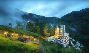 a hotel on a hill next to a river at Blanket Hotel & Spa in Munnar