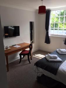 una camera d'albergo con scrivania, letto, scrivania e sedia di The Red Lion a Hythe