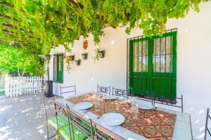 a table in a patio with green doors and vines at Huerta la Pimentada in Palma del Río