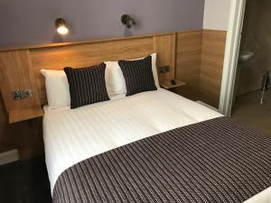 a bed with black and white sheets and pillows at Kennedys B&B Drumcondra in Dublin