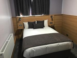 a small bedroom with a bed with black and white pillows at Kennedys B&B Drumcondra in Dublin