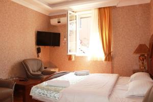 Habitación de hotel con cama, silla y ventana en Hotel Elegant Garden en Batumi