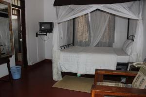 a bedroom with a white bed with a canopy at Kindoroko Hotel in Moshi