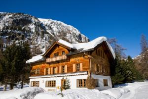 una casa de madera con nieve encima en Gasthaus Spinas en Bever