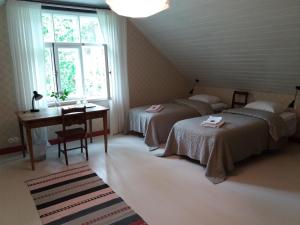 a bedroom with two beds and a desk and a window at Altraja B&B in Alavere