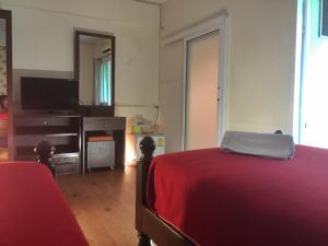 1 dormitorio con cama roja y TV en T.U.B. Mansion, en Nonthaburi