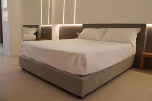uma cama com lençóis brancos e almofadas num quarto em Seven Suite em Gallipoli