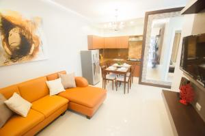 a living room with an orange couch and a kitchen at NF Suites in Davao City