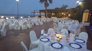 a banquet hall with white tables and chairs at night at Santa Tecla Palace in Acireale