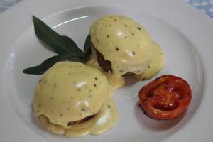 a plate of food with twoached eggs and a tomato at Devocean Eco Adventure Lodge in Ponta do Ouro