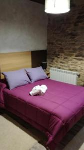 a white animal laying on top of a purple bed at Albergue Pension Porta Santa in Baleira