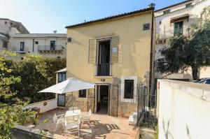 - une terrasse avec un parasol et des chaises devant un bâtiment dans l'établissement Noto Garden Holiday Home, à Noto