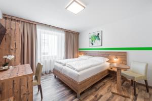 Un dormitorio con una cama, un escritorio y una mesa. en Hotel "City Rooms Wels", en Wels