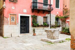 Un edificio rosso con una porta nera e un secchio di Hotel Cannaregio 2357 a Venezia