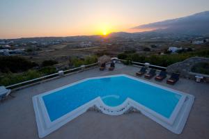 a swimming pool on the roof of a house with the sunset at Tatiana Villa & Apartments in Klouvas