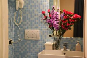 a bathroom with a vase of flowers on the sink at B&B Domus Piazza del Popolo in Rome +22 photos