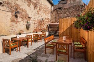 un patio con mesas y sillas de madera y una parrilla en Blumenhaus Sibiu, en Sibiu