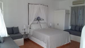 um quarto branco com uma cama e uma cadeira em Sarakiniko View Studios em Mandrakia