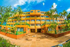 an orange building with palm trees in front of it at Constellation Apartments in Kampala