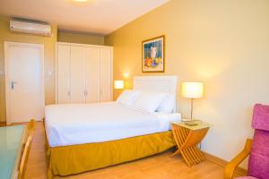 a bedroom with a large white bed and a chair at Constellation Apartments in Kampala