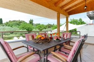 einen Tisch mit Stühlen und eine Obstschale auf dem Balkon in der Unterkunft Apartments Čolak in Zadar