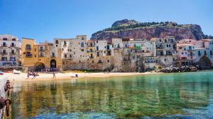a group of buildings on a beach next to the water at B&B Pepito in Cefalù