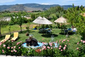 un giardino con tavoli, sedie e ombrelloni di Shine Studios a Skala Kallonis