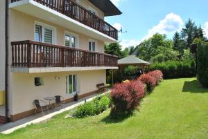 a house with a balcony and a grass yard at Nad Jeziorem Domki i Pokoje 781-281-434 in Polańczyk