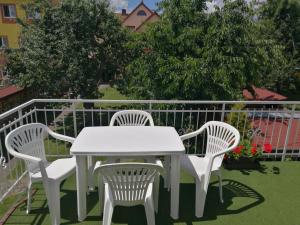 d'une table blanche et de quatre chaises sur un balcon. dans l'établissement Apartman v zahrade, à Nová Včelnice