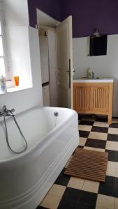 a white bath tub in a bathroom with a checkered floor at Magnifique Maison de Caractère FAMILIALE 12 Couchages in Écouché