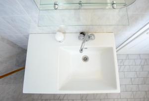 a white sink in a white tiled bathroom at Myros Studios in Argostoli