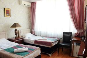 sypialnia z 2 łóżkami, krzesłem i oknem w obiekcie Hotel Elegant Garden w mieście Batumi