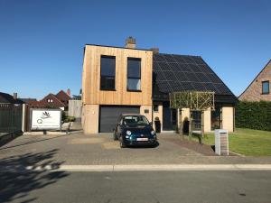 une voiture garée devant une maison dotée d'un toit solaire dans l'établissement Q Studio, à Herzele