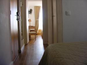 a hallway with a bed and a chair in a room at Hôtel La Flore in Villefranche-sur-Mer
