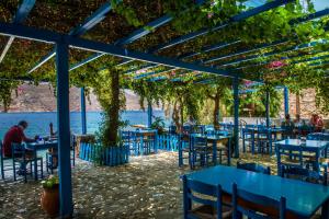 a restaurant with blue tables and chairs under a pergola at Faros Rooms in Livadia
