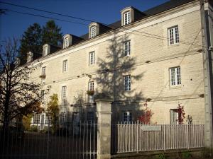 un gran edificio de ladrillo blanco con una valla en Le Moulin de Poilly, en Poilly-sur-Serein