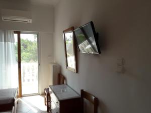 a room with a tv on a wall with a table at Posidonia Pension in Amarinthos