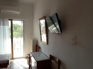 Habitación con TV en la pared y mesa. en Posidonia Pension, en Amarinto
